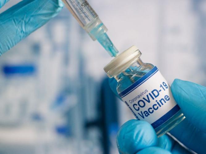 close up shot of a covid vaccine and a syringe