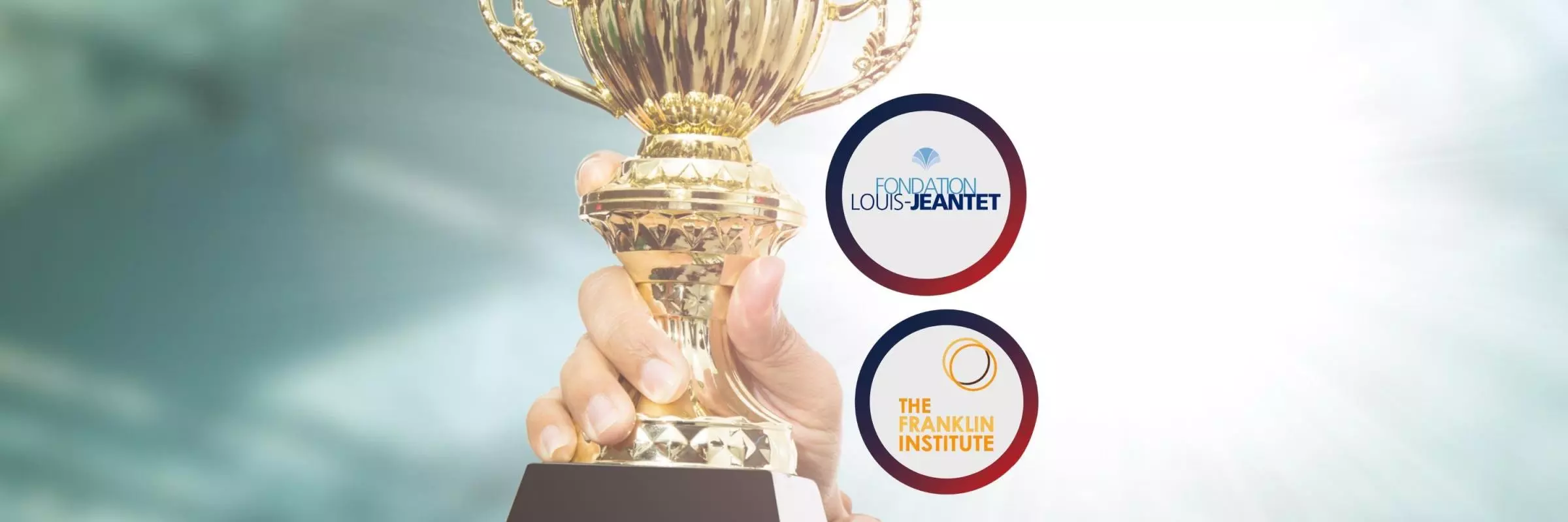 An image with "Louis-Jeantet Foundation logo" and "Benjamin Franklin Institute logo" in front of a background with hands holding a golden award.